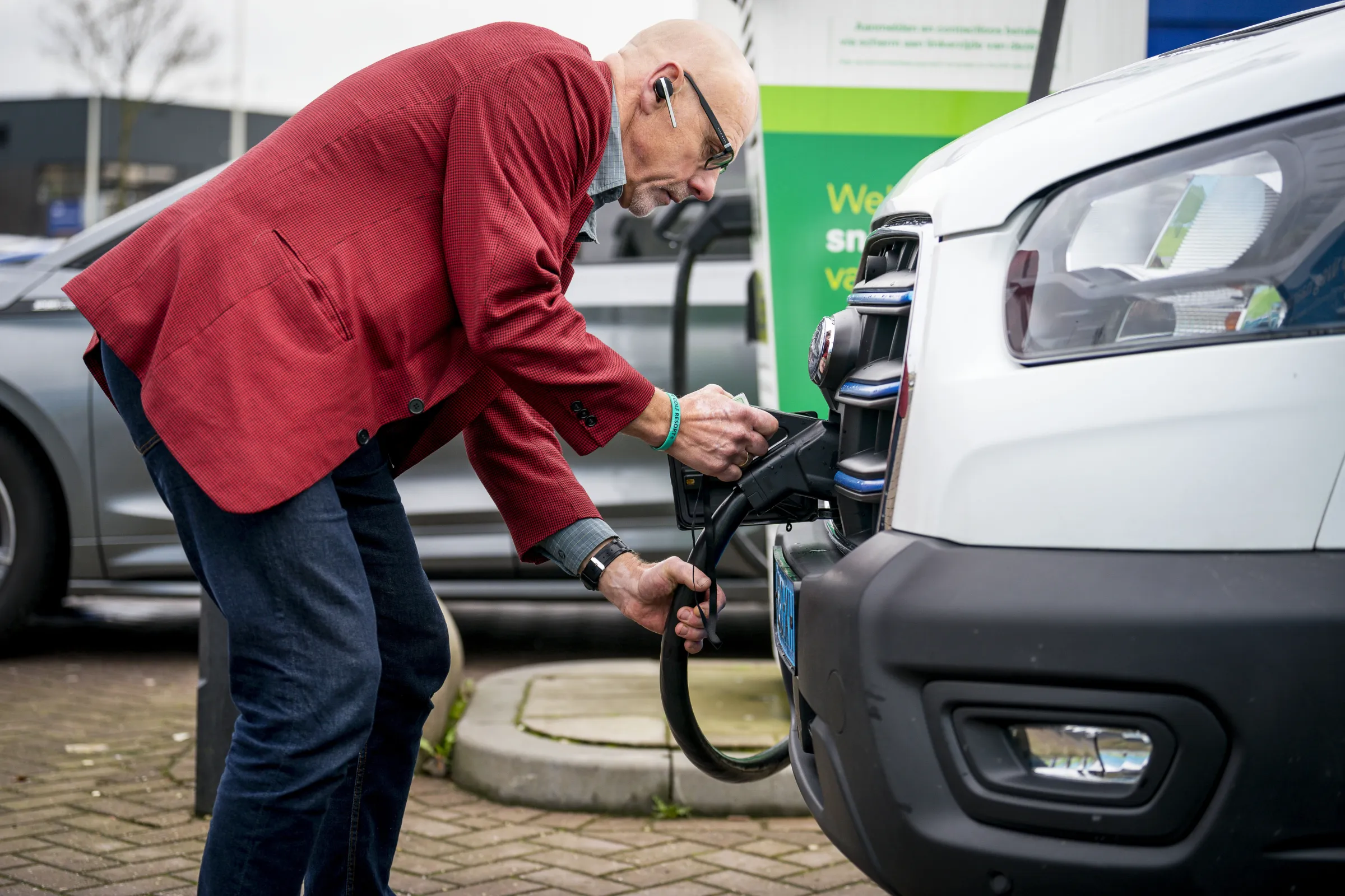 Man zet zijn bus aan de elekrische laadpaal.