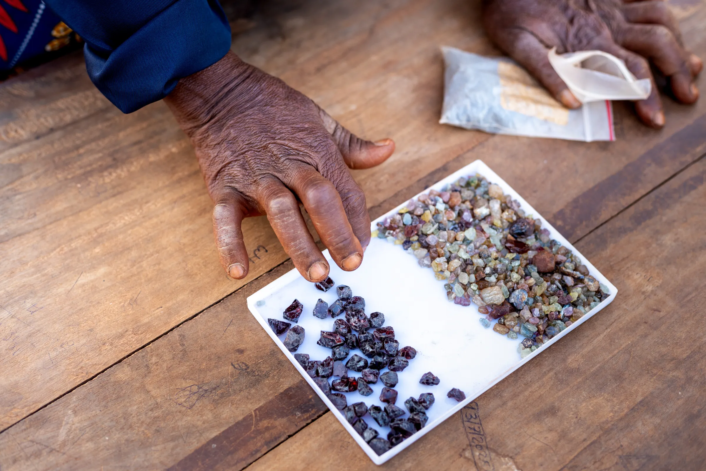 Handen van een mijnwerker die edelstenen sorteert op een tafel in Tanga, Tanzania.