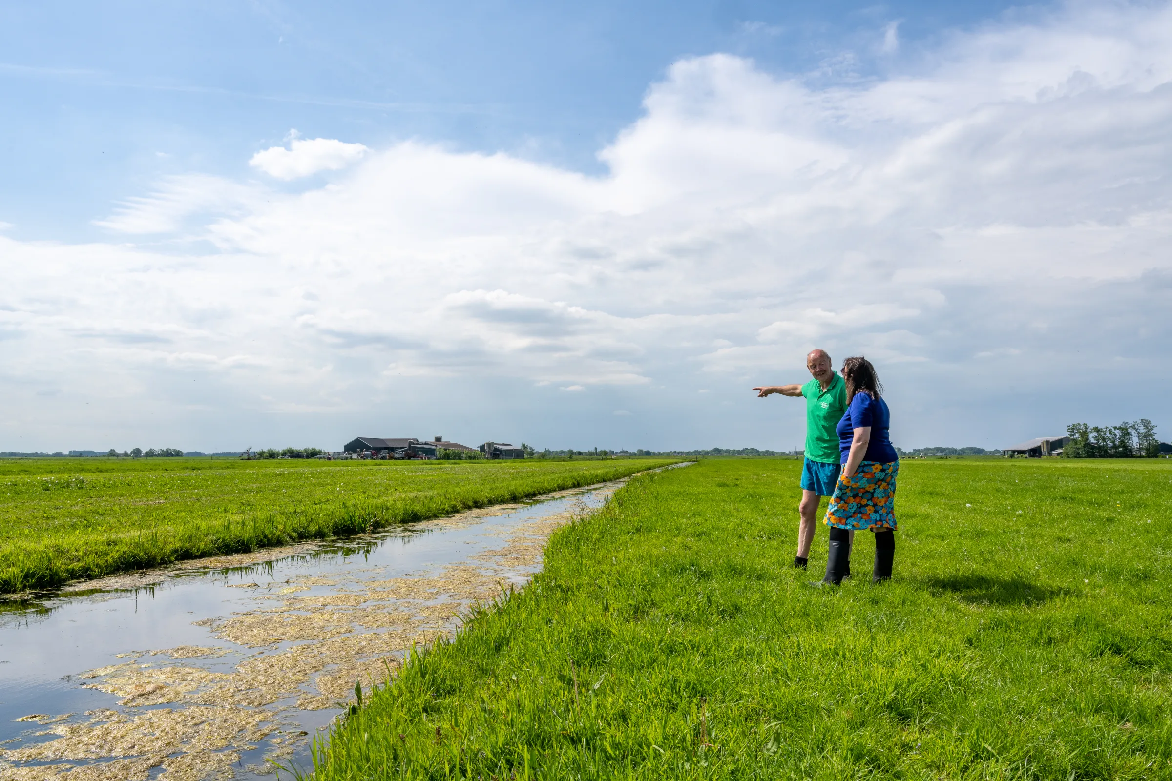 Boer en vrouw in de wei bij sloot