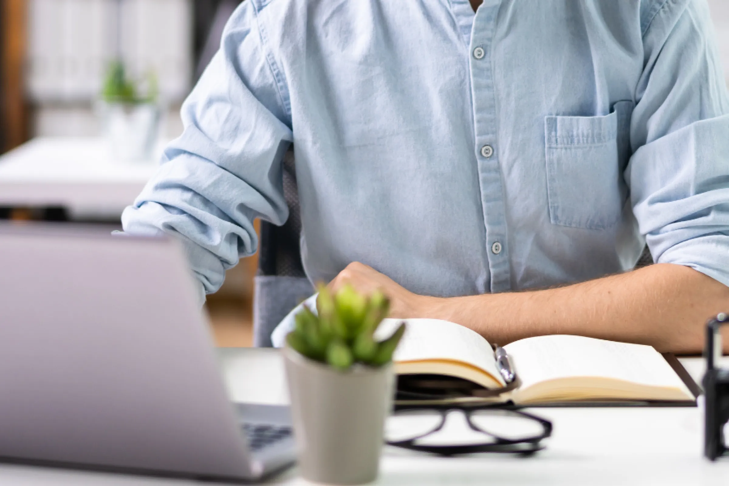 Persoon aan een bureau zit achter laptop