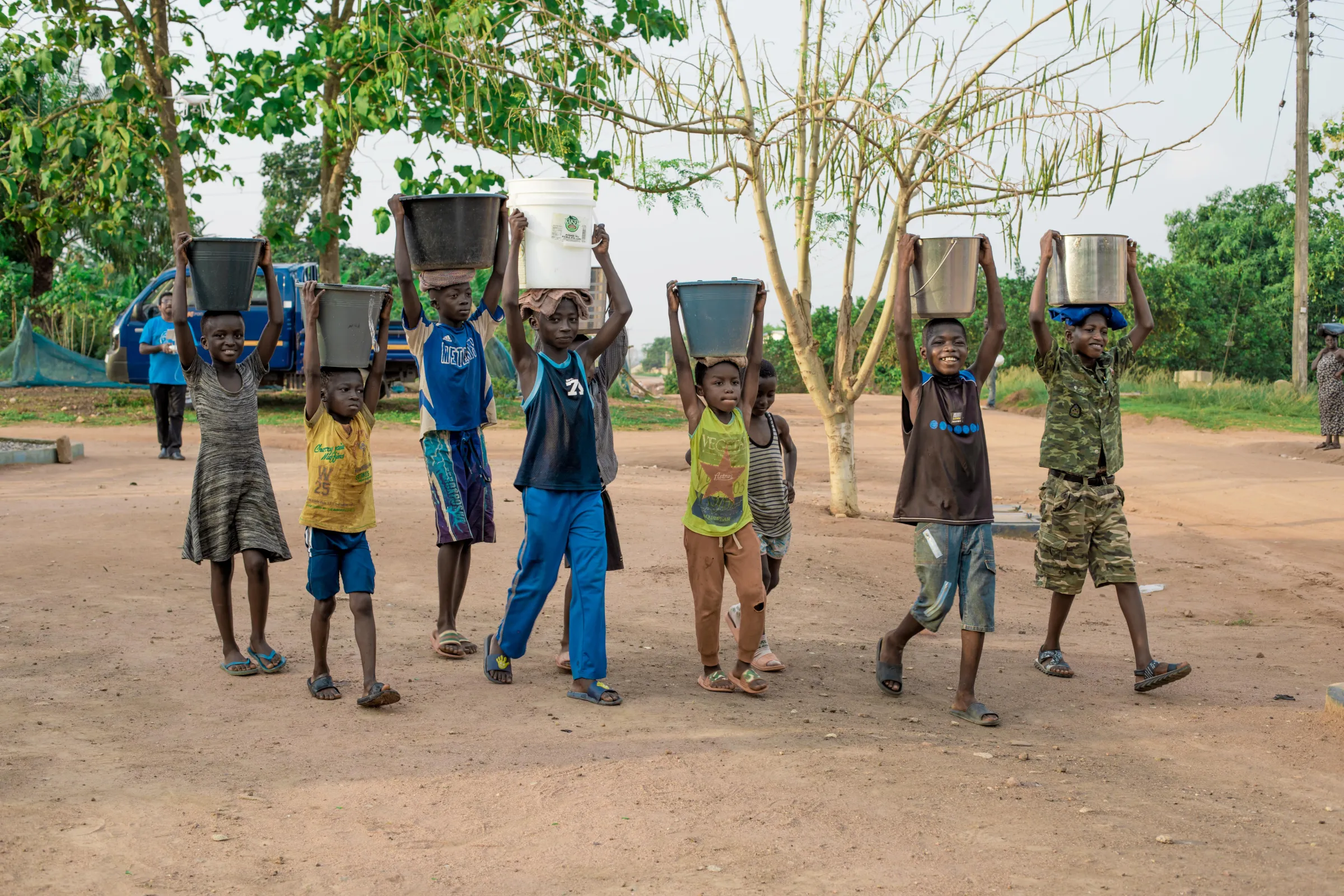 Children carrying buckets of water on their heads