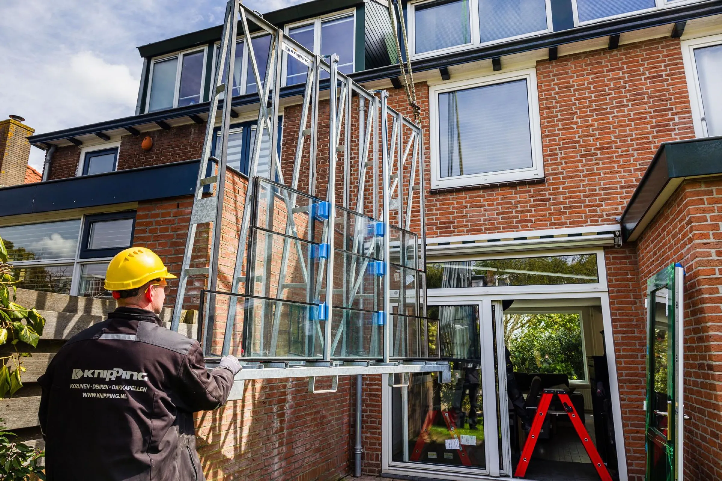 Mens draagt een nieuwe glasplaat naar een woning om te verduurzamen