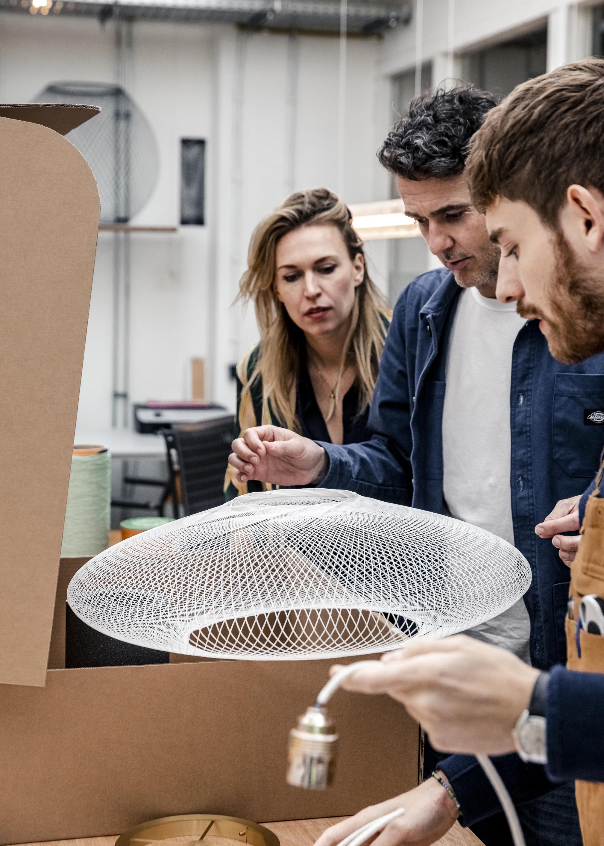 Medewerkers van Atelier Robotiq kijken naar een van hun lampen