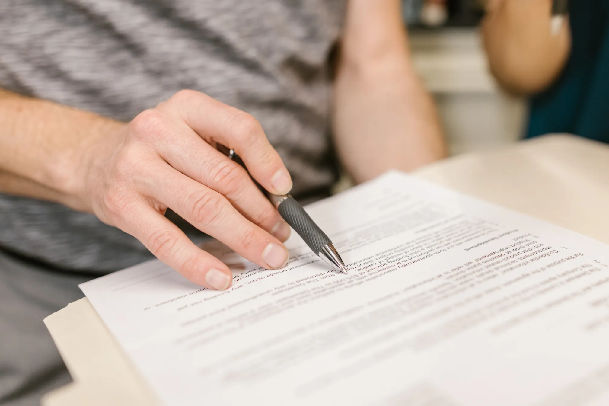 Close-up van een hand met pen en een opgesteld contract