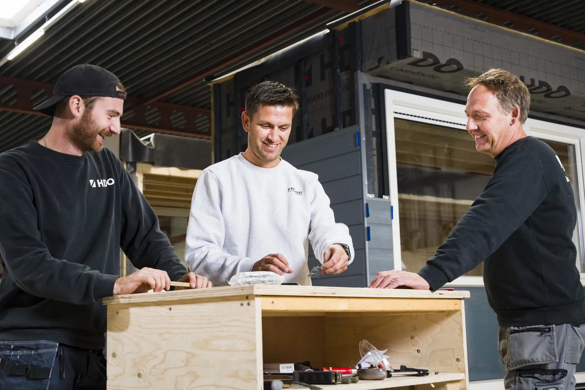 3 personen aan desk productiehal HDO Groep